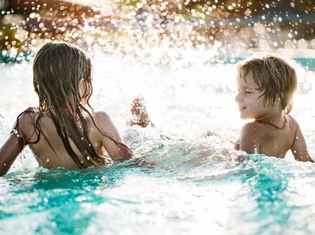 two children playing in a swimming pool at sunset