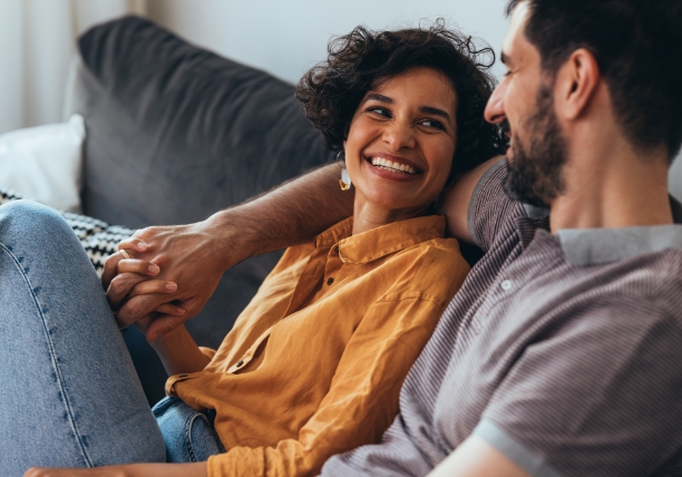 couple sitting on a couch holding hands and smiling