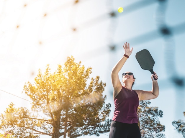 woman playing pickleball outside in the sun
