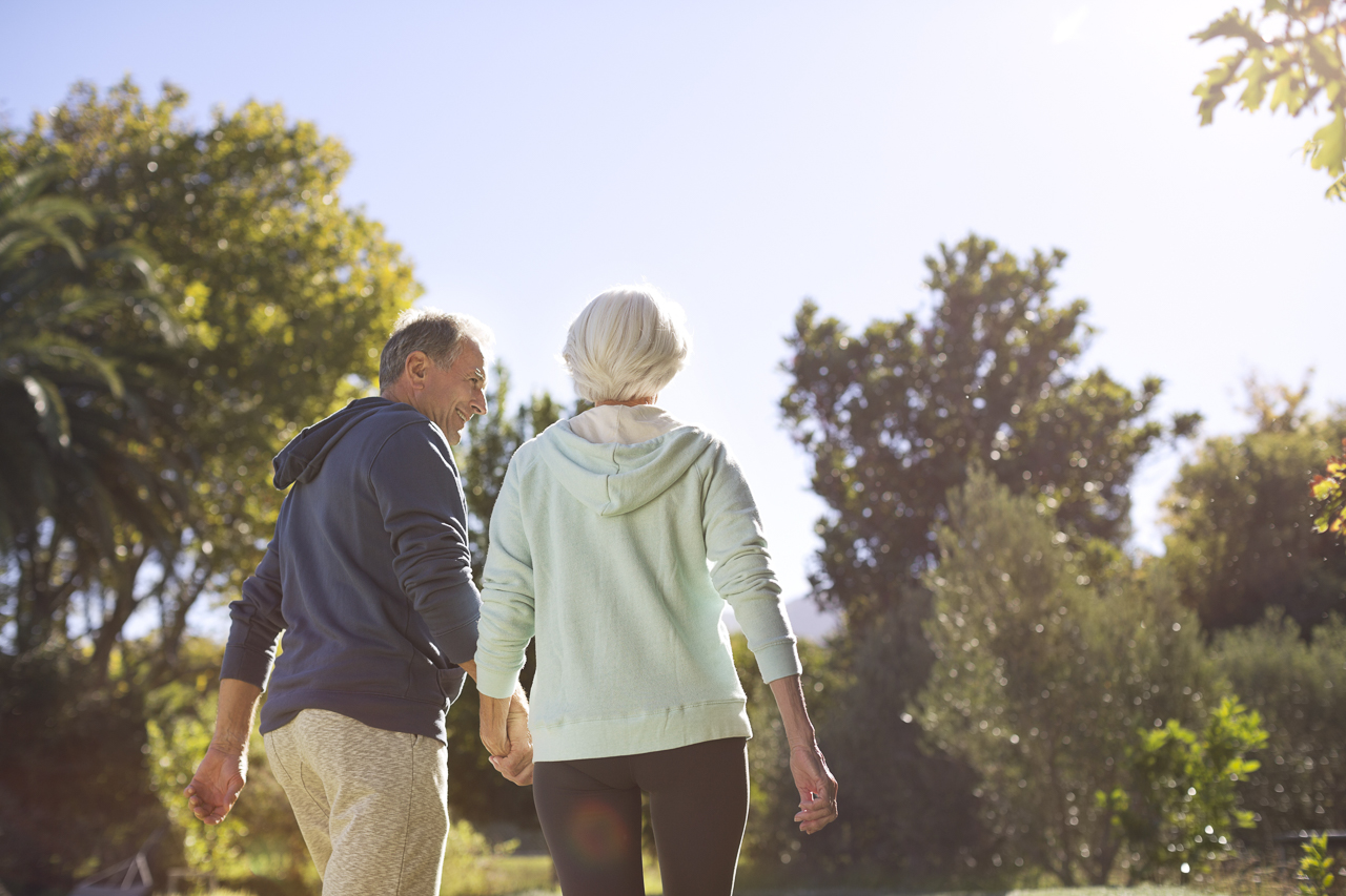 Senior couple holding hands and walking in park - Riversong developer Pulte Homes emphasizes fostering a lifestyle like this.
