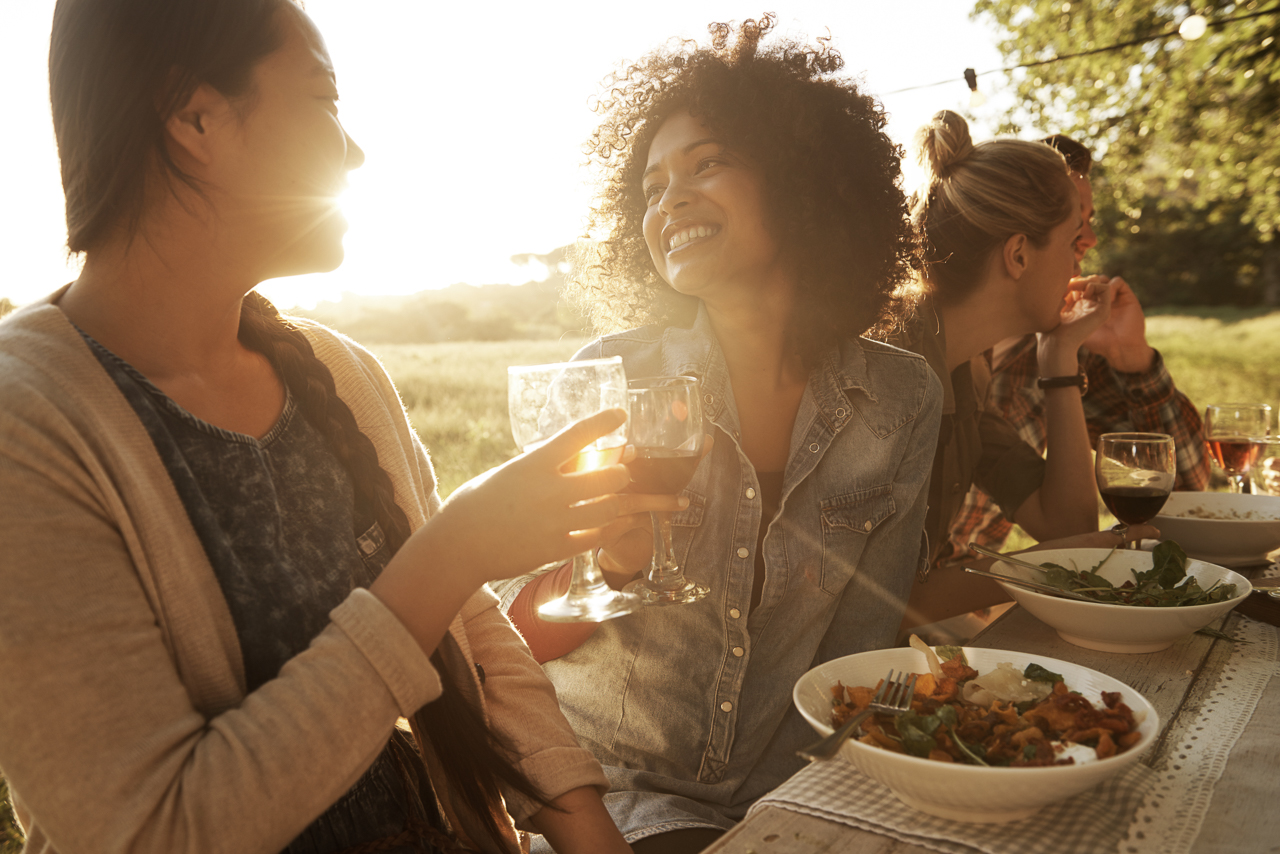 Shot of two women enjoying themselves at a late afternoon outdoor meal